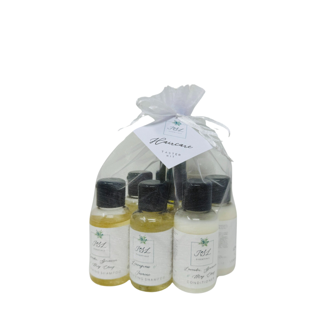 Een klein tasje met witte en gele reisflesjes met verzachtende shampoo en conditioner, met zwarte doppen, met het label JSL Essentials Haircare Taster Kit (TRAVEL-SIZE).