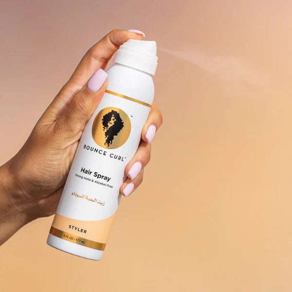 Een hand houdt een bus Bounce Curl Hair Spray 177ml (FULL-SIZE) vast tegen een neutrale achtergrond, voor perfecte krullen tegen pluis.